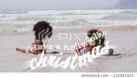 Lying siblings wearing swimwear and snorkel gear exploring shoreline at beach, with inflatable ring 132981825