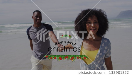 Walking couple holding hands along sandy shore under cloudy sky, with holiday greeting graphic Walking couple holding hands along sandy shore under cloudy sky, with holiday greeting graphic 132981832