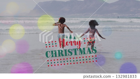Running siblings wearing striped trunks and bikini on beach, with Merry Christmas overlay 132981833