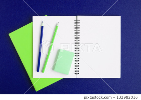 Notebook with pencil. White page on dark violet color background, spiral notepad on table. Top view Copy Space. Blank paper sheet office supplies. Greeting card mockup. Modern Minimal business mock up 132982016