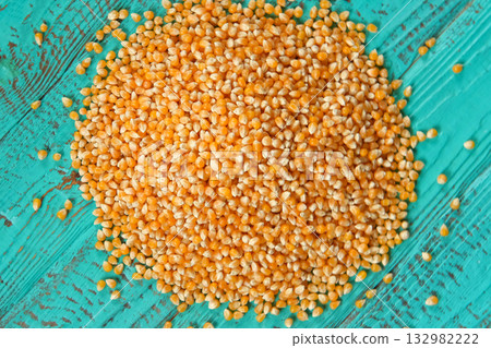 Corn seeds. Pile of raw corn grains closeup on blue wood rustic table. Husbandry concept. Yellow maize, Zea mays, particles Full Frame. Top View. Organic production. Food background Corn seeds. Pile of raw corn grains closeup on blue wood rustic table. Husbandry concept. Yellow maize, Zea mays, particles Full Frame. Top View. Organic production. Food background 132982222