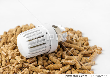 Wooden Pellets with Thermostat. Thermostatic Valve Head Isolated on White Background. Renewable Source of Heating. Biofuel. Ecologic Fuel made from Biomass. The Alternative Energy Source. Gas Crisis. Wooden Pellets with Thermostat. Thermostatic Valve Head Isolated on White Background. Renewable Source of Heating. Biofuel. Ecologic Fuel made from Biomass. The Alternative Energy Source. Gas Crisis. 132982433