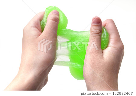 Hand Playing with textured slime on white background. Teen hand holding green shining slime with bubbles, stretching gooey substance. Teenage Girl squeezing slime toy to the sides. Liquid toy. Handgum 132982467