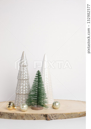 Modern Christmas trees. Decorative Beige, White and Green Christmas Decoration on a Wooden Stand with a Gray background. Nordic Festive Decor. Boho, Scandinavian Style Design. Trendy Minimal Ornament. 132982577