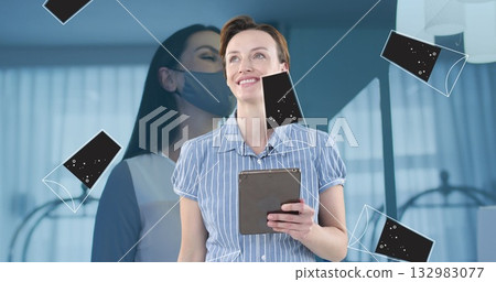 Holding tablet and looking upward in office, showing masked overlay and floating phone icons Holding tablet and looking upward in office, showing masked overlay and floating phone icons 132983077