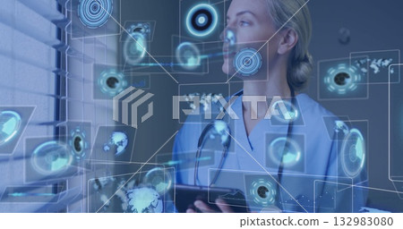Reviewing tablet data while wearing scrubs and stethoscope at clinic, projecting data panels Reviewing tablet data while wearing scrubs and stethoscope at clinic, projecting data panels 132983080