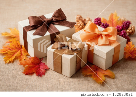 Festive autumn gifts and yellow maple leaves. Fall season presents pile. Stack of gift boxes tied with ribbons on beige background. Thanksgiving holiday, birthday concept. Anniversary composition 132983081