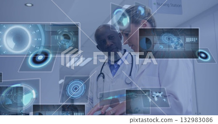 Reviewing holographic data, two doctors in lab coats, stethoscopes, ID badges at nursing station 132983086