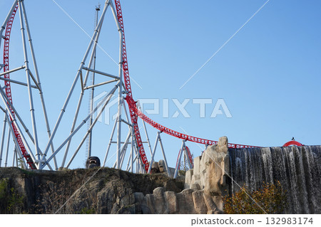 Red and white roller coaster track structure with waterfall at amusement park 132983174