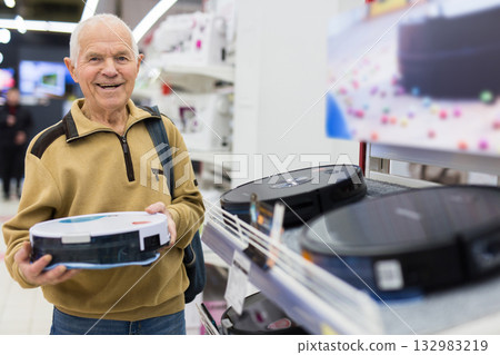 elderly man choosing robot vacuum cleaner in showroom of electrical appliance store 132983219
