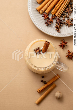 Traditional Indian masala chai tea with milk and spices in a cup on a beige background 132983562