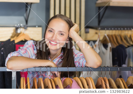 Adult woman in plaid shirt leaning over metal rack in store showcasing wooden hangers, shelving Adult woman in plaid shirt leaning over metal rack in store showcasing wooden hangers, shelving 132983622