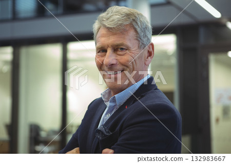 Senior male professional standing in office with partitions, wearing navy blazer with pocket square 132983667