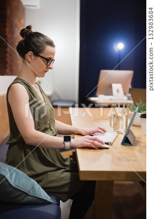 Female professional typing on tablet with keyboard, coffee cup at office by brick wall, copy space Female professional typing on tablet with keyboard, coffee cup at office by brick wall, copy space 132983684