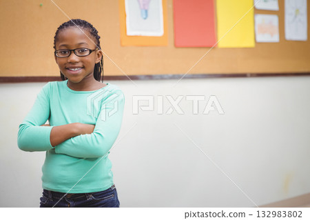 African American child standing and smiling in classroom by cork board with drawings, copy space African American child standing and smiling in classroom by cork board with drawings, copy space 132983802
