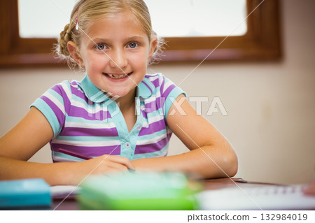 School-age girl smiling and sorting colorful notebooks and pencil case on wooden desk in study area School-age girl smiling and sorting colorful notebooks and pencil case on wooden desk in study area 132984019