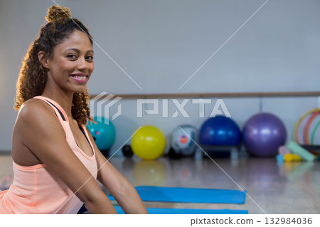Smiling African American woman practicing yoga on blue mat with balls and weights, copy space 132984036