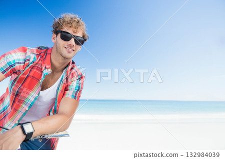 Man leaning on bicycle handlebars on beach wearing sunglasses and smartwatch, copy space Man leaning on bicycle handlebars on beach wearing sunglasses and smartwatch, copy space 132984039
