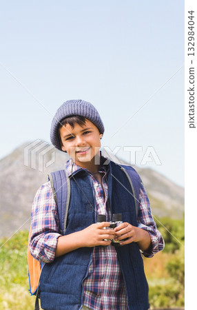 Middle Eastern boy standing on mountain path holding binoculars and wearing orange backpack 132984044