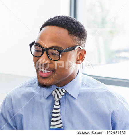 African American man standing by office window speaking and smiling wearing eyeglasses and tie 132984182
