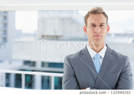 Gray-suited man standing by balcony railing looking confident in light-blue tie, copy space 132984201