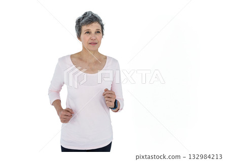 Senior woman jogging in place wearing light pink top, leggings, fitness tracker in studio Senior woman jogging in place wearing light pink top, leggings, fitness tracker in studio 132984213