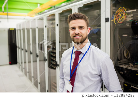Male IT professional wearing light shirt, red tie inspecting server rack in data center, copy space Male IT professional wearing light shirt, red tie inspecting server rack in data center, copy space 132984282