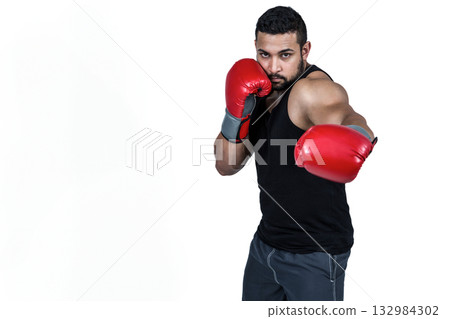 Male boxer throwing straight punch in studio against white backdrop wearing red gloves, copy space Male boxer throwing straight punch in studio against white backdrop wearing red gloves, copy space 132984302