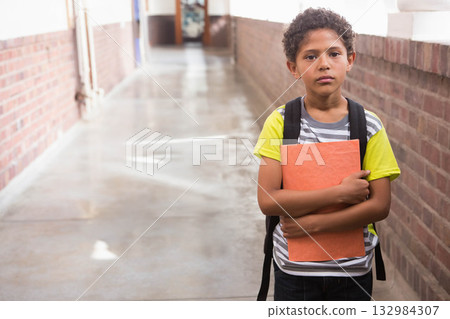 African American boy standing in school corridor holding orange folder with backpack, copy space African American boy standing in school corridor holding orange folder with backpack, copy space 132984307