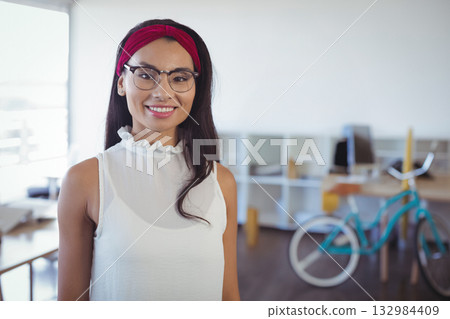 Mid adult woman smiling in office wearing dark rimmed eyeglasses and red headband with teal bicycle 132984409