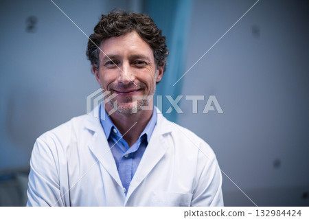 Man standing in laboratory wearing white lab coat over light blue shirt with numeric wall labels 132984424