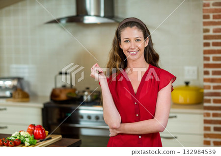 Woman chopping fresh broccoli and red bell pepper on wooden cutting board at modern kitchen island Woman chopping fresh broccoli and red bell pepper on wooden cutting board at modern kitchen island 132984539