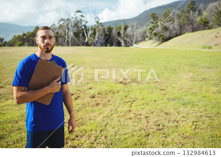 Man holding clipboard, standing in grassy meadow on left side under cloudy sky, copy space 132984613