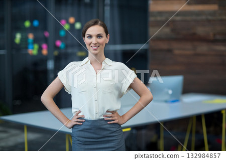 Teenage girl in business attire standing by office table with laptop and colorful sticky notes 132984857