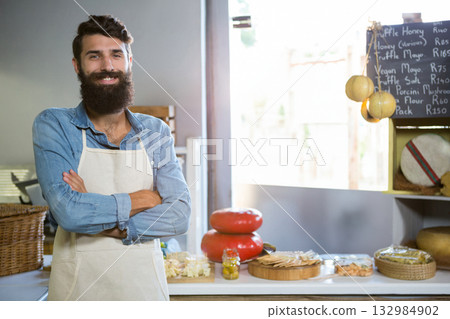 Male shopkeeper in apron smiling and showing cheese wheels and olives in cheese shop, copy space Male shopkeeper in apron smiling and showing cheese wheels and olives in cheese shop, copy space 132984902