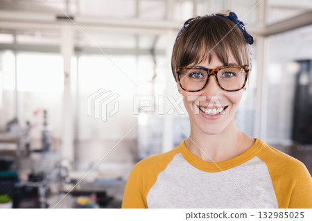 Woman standing at open plan office wearing fabric headband and tortoiseshell eyeglasses, copy space Woman standing at open plan office wearing fabric headband and tortoiseshell eyeglasses, copy space 132985025