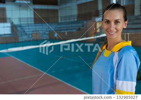 African American woman volleyball player wearing blue jersey standing by net in gym, copy space African American woman volleyball player wearing blue jersey standing by net in gym, copy space 132985027