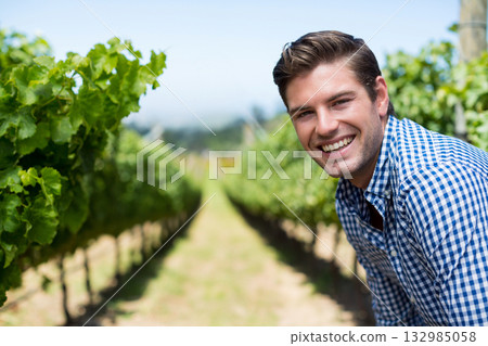 Man with fair skin leaning between grapevine rows smiling at vineyard under sunny sky, copy space Man with fair skin leaning between grapevine rows smiling at vineyard under sunny sky, copy space 132985058