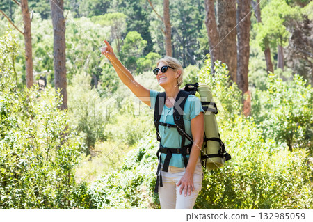 Senior woman walking on sunlit forest path carrying green sleeping pad, with sunglasses, copy space Senior woman walking on sunlit forest path carrying green sleeping pad, with sunglasses, copy space 132985059