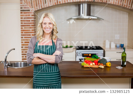 mid-thirties woman chopping vegetables on wooden island next to sink faucet and olive oil bottle 132985125