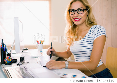 Woman working on digital design in home office wearing striped top with graphics tablet, copy space 132985149