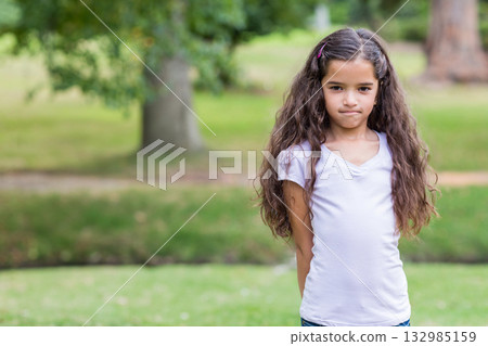 Girl standing in well-kept public park with pink hair clip in hair near tree, copy space 132985159