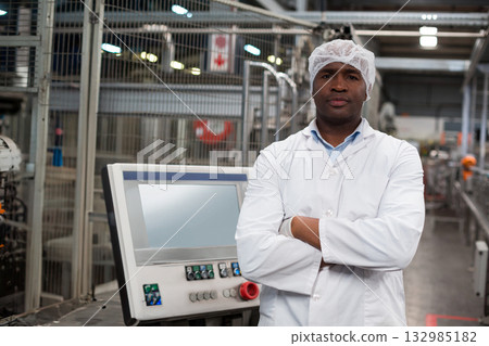 Mid adult African American man in lab coat inspecting touchscreen panel on plant floor, copy space 132985182