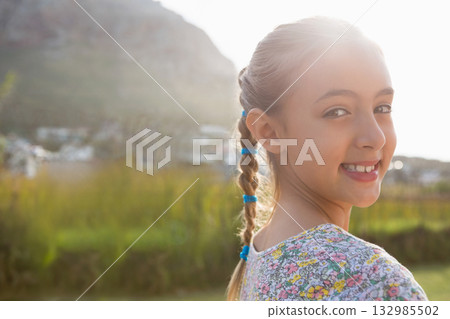 Child girl smiling in grassy field with blue braided hair ties and floral shirt, copy space Child girl smiling in grassy field with blue braided hair ties and floral shirt, copy space 132985502