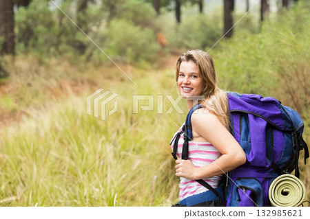 Female hiker standing on pine forest trail carrying purple backpack with rolled mat, copy space Female hiker standing on pine forest trail carrying purple backpack with rolled mat, copy space 132985621