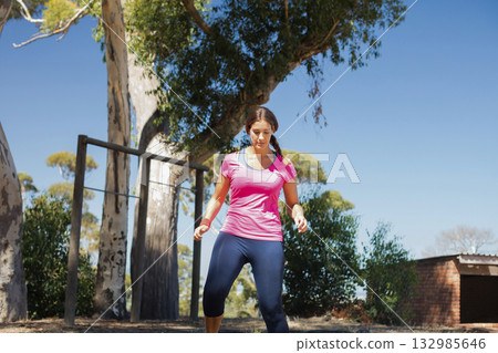 Female exerciser standing under eucalyptus trees wearing sportswear and gripping metal pull-up bar Female exerciser standing under eucalyptus trees wearing sportswear and gripping metal pull-up bar 132985646