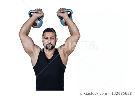 Man lifting grey kettlebells with red accents overhead in studio wearing black sleeveless tank top Man lifting grey kettlebells with red accents overhead in studio wearing black sleeveless tank top 132985698