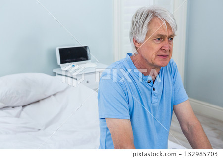 Senior man sitting on edge of bed in bedroom, tapping digital tablet screen, copy space Senior man sitting on edge of bed in bedroom, tapping digital tablet screen, copy space 132985703