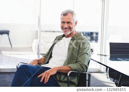Senior man smiling in office chair at conference table with notebook and pen, copy space 132985855