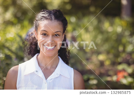 African American woman standing and smiling in sunlit garden wearing sleeveless collared shirt African American woman standing and smiling in sunlit garden wearing sleeveless collared shirt 132985875